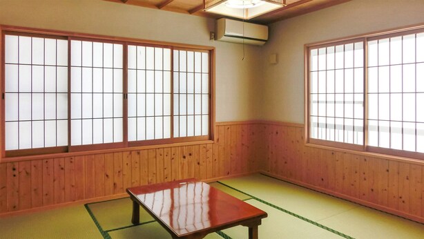 Um quarto japonês tradicional com tatames, biombos shoji e uma mesa de madeira baixa.