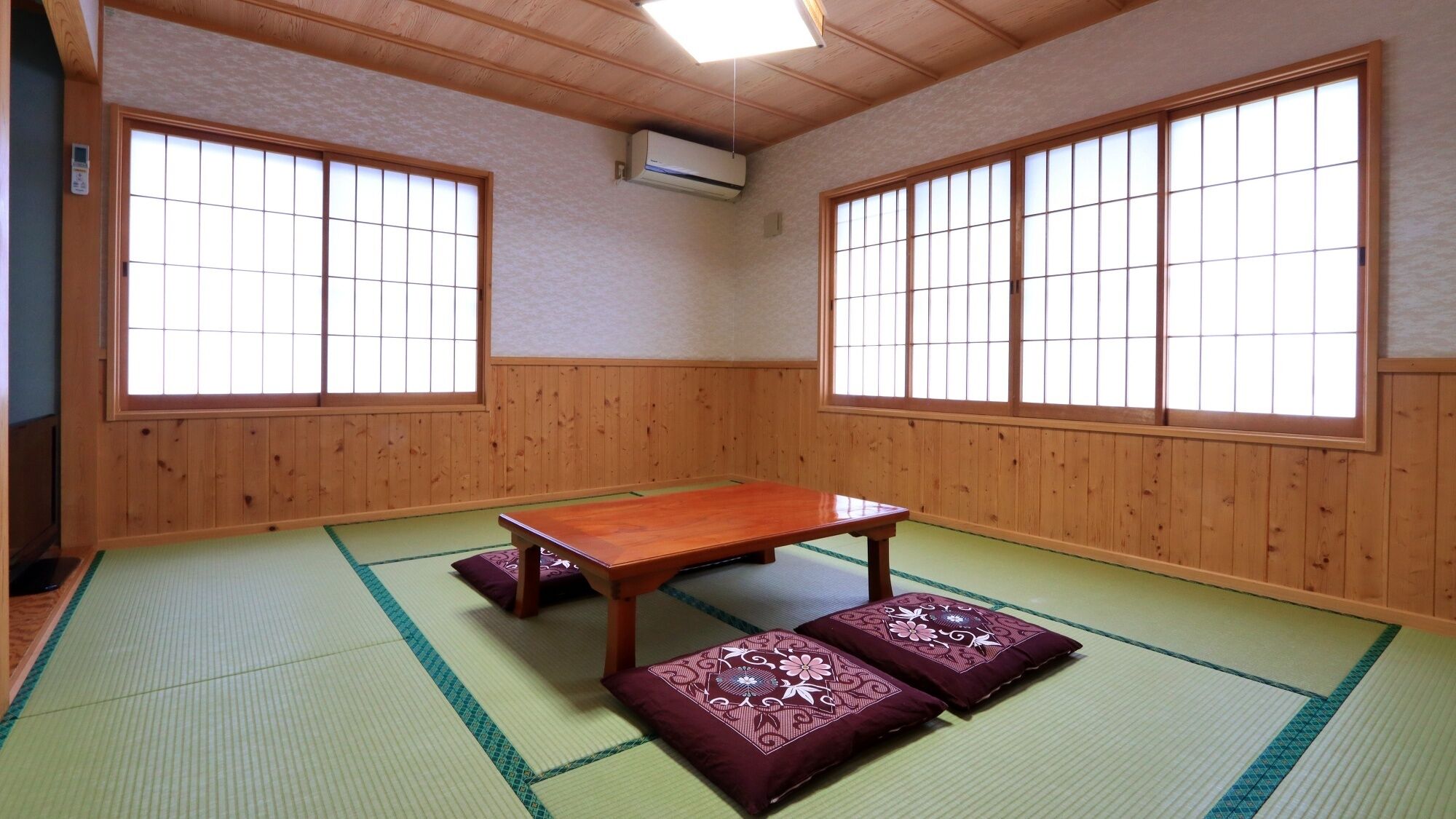 Egy tatamival borított szoba, alacsony, fából készült asztallal, tatami szőnyegekkel és shoji típusú, papírral borított, tolókeretes ablakokkal.