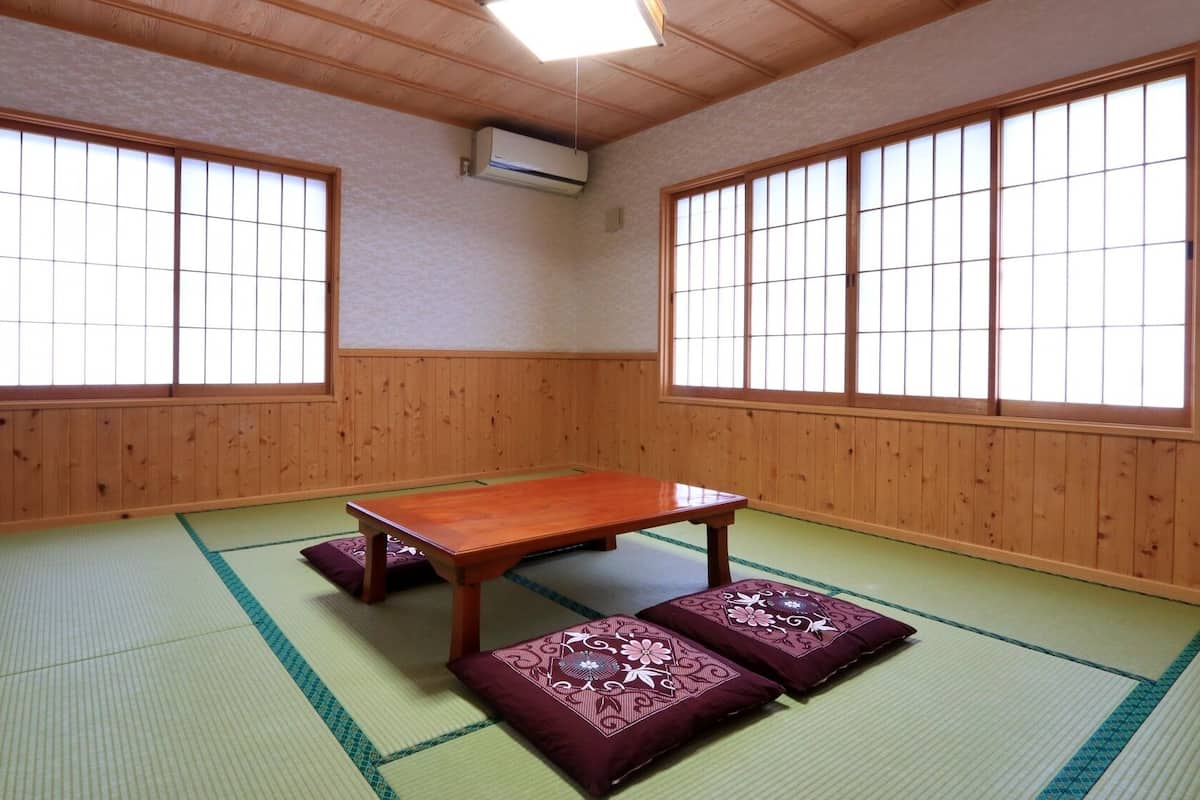 Une pièce au sol recouvert de tatamis, avec une petite table en bois, des tapis de tatami et des paravents coulissants.