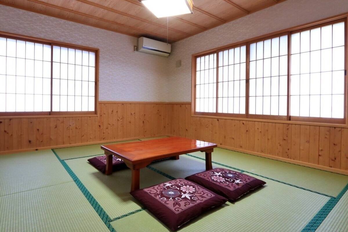 Une pièce de style japonais traditionnel, avec un sol recouvert de tatamis, une table en bois et des paravents en papier.