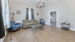 A spacious living room with a sofa, two armchairs, a coffee table, and a chandelier. - Near Chattahoochee River & Shops - Central Duplex (Columbus)
