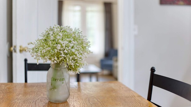 A wooden table with a glass jar containing white flowers. - Near Chattahoochee River & Shops - Central Duplex (Columbus)
