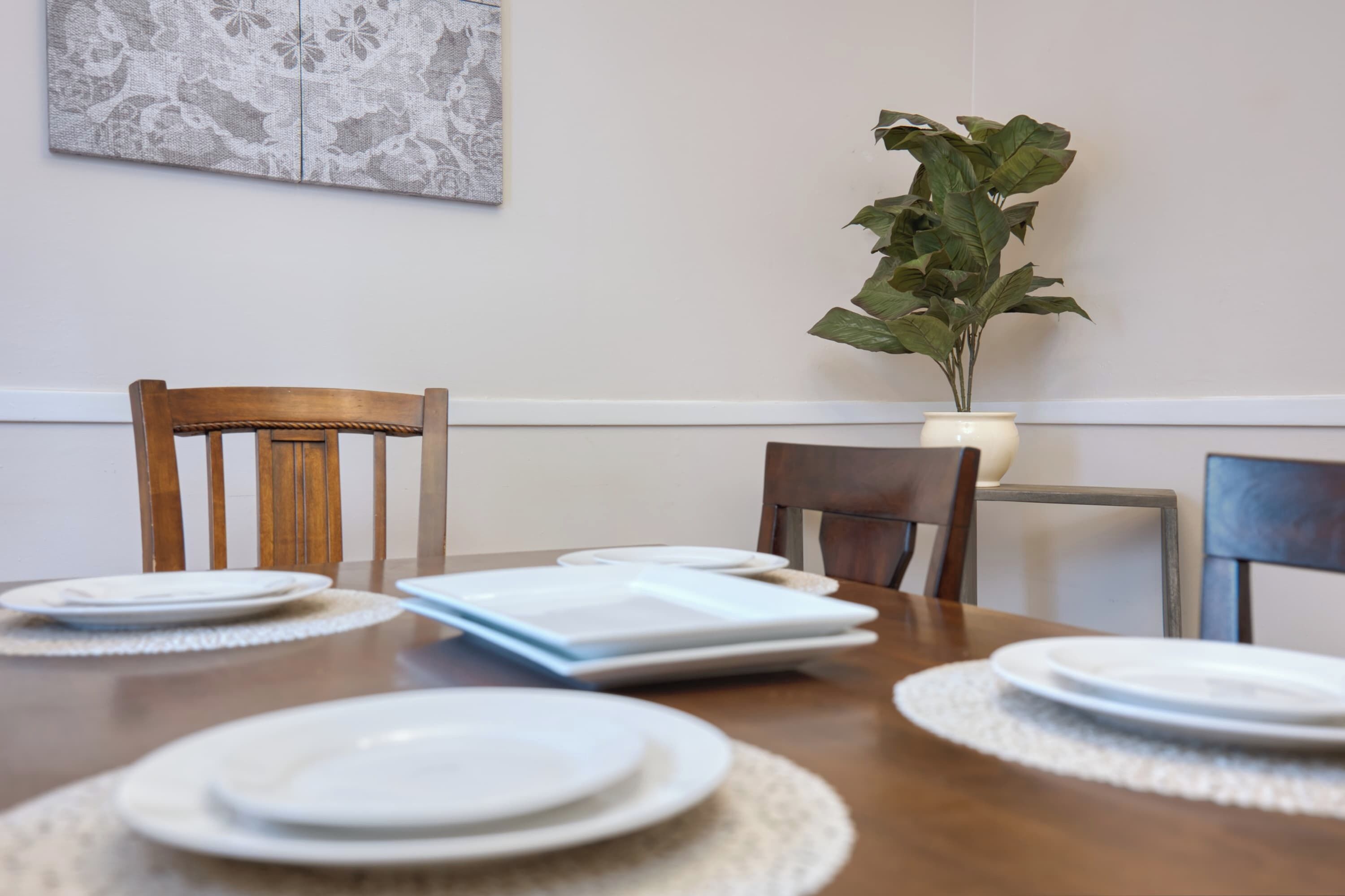 A dining table with plates, a book, and a potted plant.