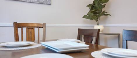 A dining table with plates, a book, and a potted plant.