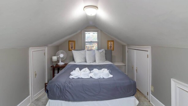 Une chambre à coucher avec un lit, un ventilateur et une fenêtre.