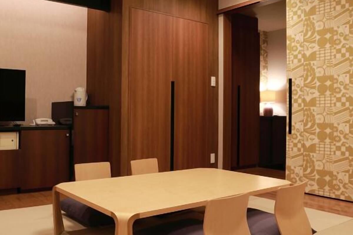 Ein modernes Zimmer mit Holztisch, Stühlen, einem Fernseher und einer Wand mit Muster.