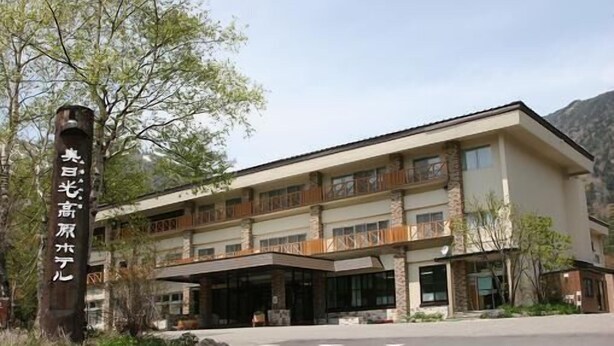 A multi-story hotel with a stone facade, large windows, and a covered entrance. - Okunikko Yumoto Onsen Okunikko Kogen Hotel (Nikko)