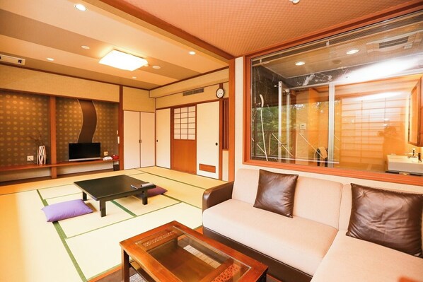 A traditional Japanese-style room with tatami flooring, a tatami mat table, a sofa, and a sliding door. - Okunikko Yumoto Onsen Okunikko Kogen Hotel (Nikko)
