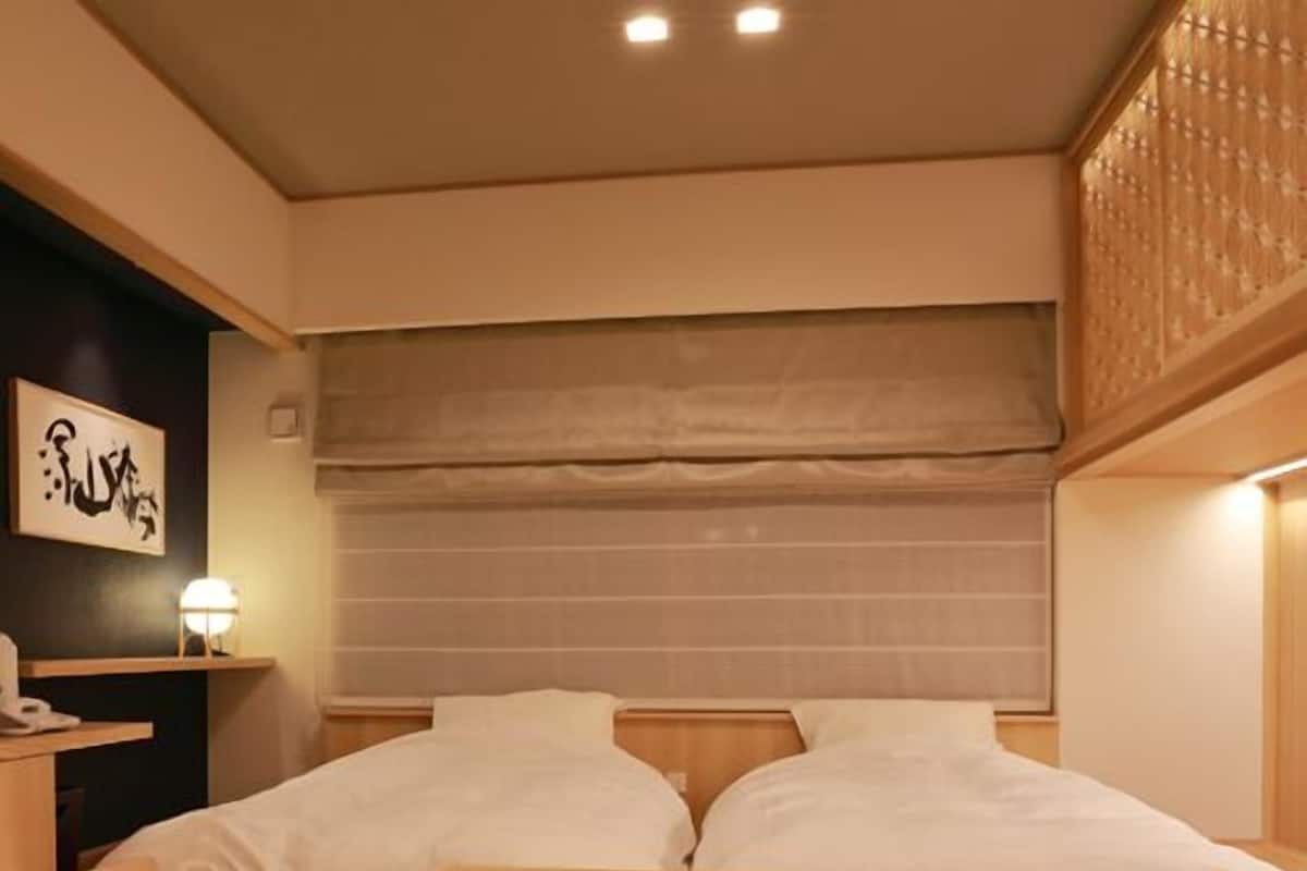 Ein Hotelzimmer mit Bett, Nachttisch und kleinem Schreibtisch mit Lampe.