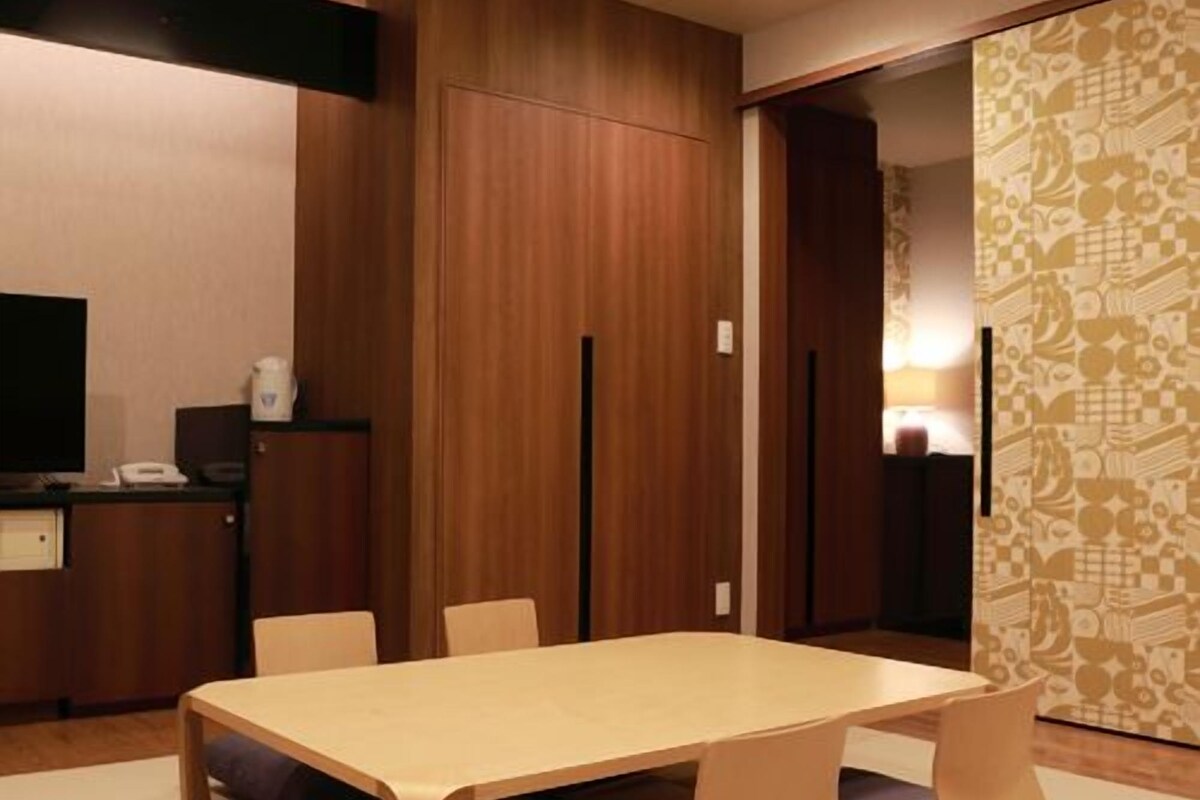 A modern room with a wooden table, chairs, a television, and a patterned wall.