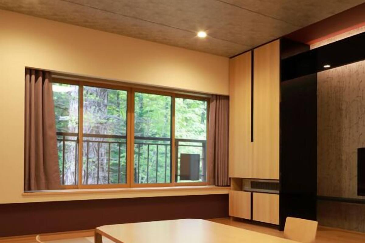 Ein modernes Zimmer mit großem Fenster, einem Holztisch und einer integrierten Küchenzeile.