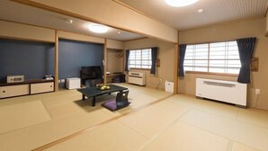 A traditional Japanese room with tatami flooring, a low table with cushions, a television, and a heater. - Okunikko Yumoto Onsen Okunikko Kogen Hotel (Nikko)