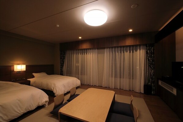 A hotel room with two beds, a small table, a TV, and a curtain backdrop. - Okunikko Yumoto Onsen Okunikko Kogen Hotel (Nikko)