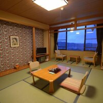 Una habitación tradicional japonesa con suelo de tatami, una mesa baja y asientos.