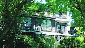 A modern house with a balcony, surrounded by lush greenery.