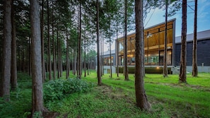 A modern building with large windows, surrounded by a forest. - Dake Onsen Soranoniwa Resort (Nihommatsu)