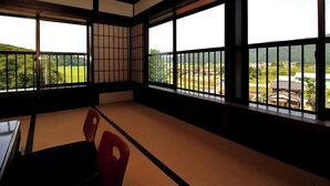 Ein Raum mit Tatami-Matten und Blick auf eine grüne Landschaft durch große Fenster.