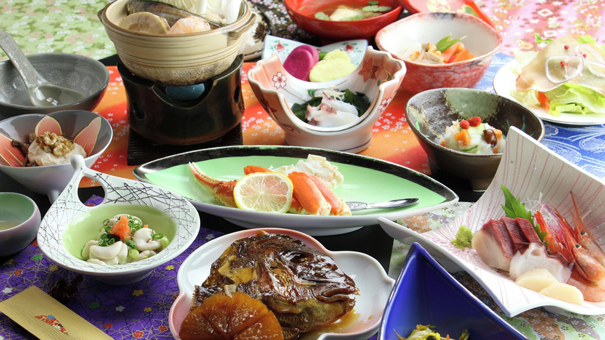A variety of dishes on a table with a floral tablecloth.