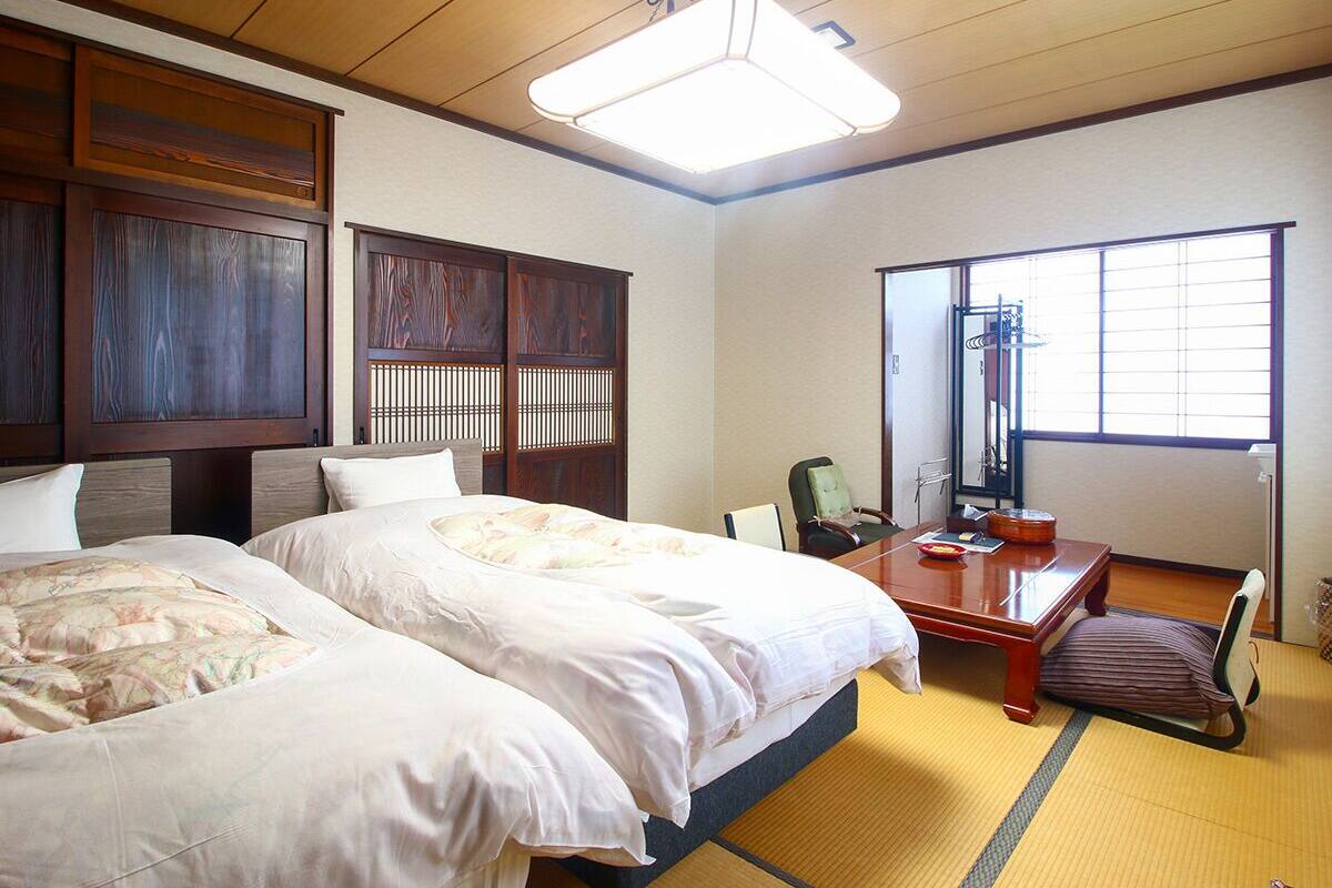 Une chambre d’hôtel avec deux lits, un bureau, une chaise, un miroir et une fenêtre.