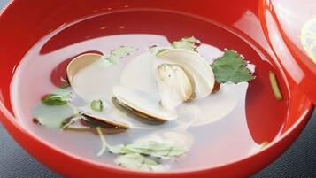 A bowl with sliced clams and herbs in water.