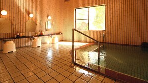 Ein nasser Boden in einem Raum mit gefliesten Wänden, einem Fenster und einer Badewanne.