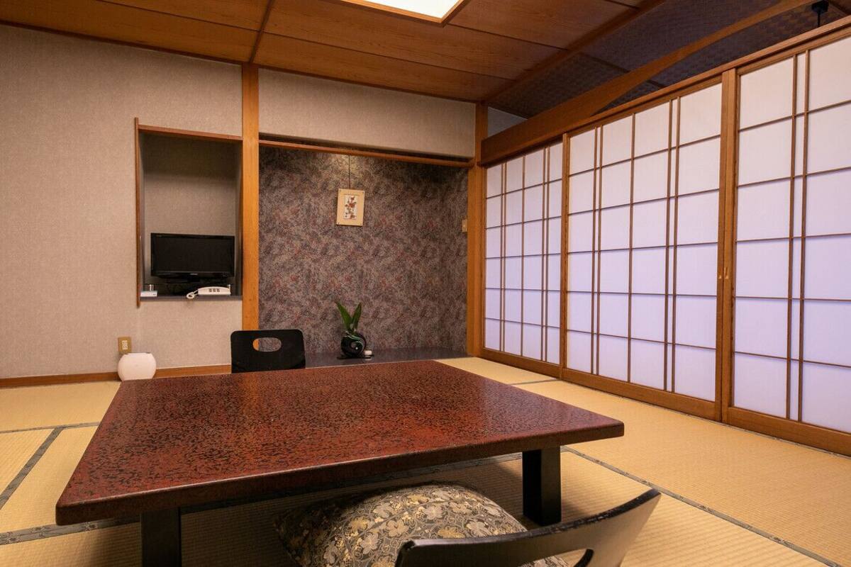 A traditional Japanese room with tatami flooring, a low table, a television, and shoji screens.