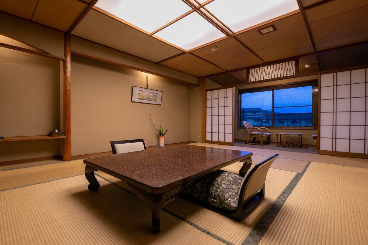 A traditional Japanese room with tatami flooring, a low table, and sliding doors.