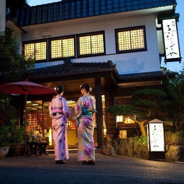 A traditional Japanese building with a tiled roof, large windows, and a signboard.