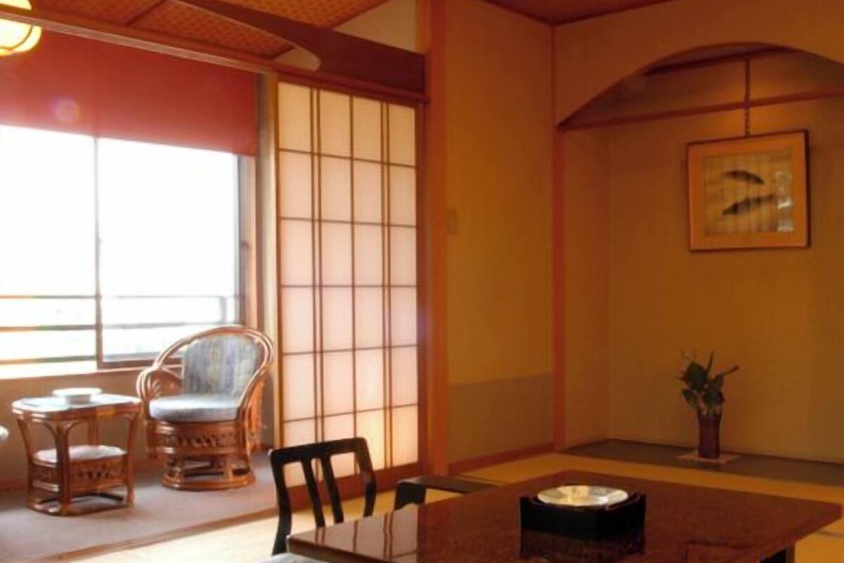 A tatami mat room with a low table, chairs, and a sliding door.