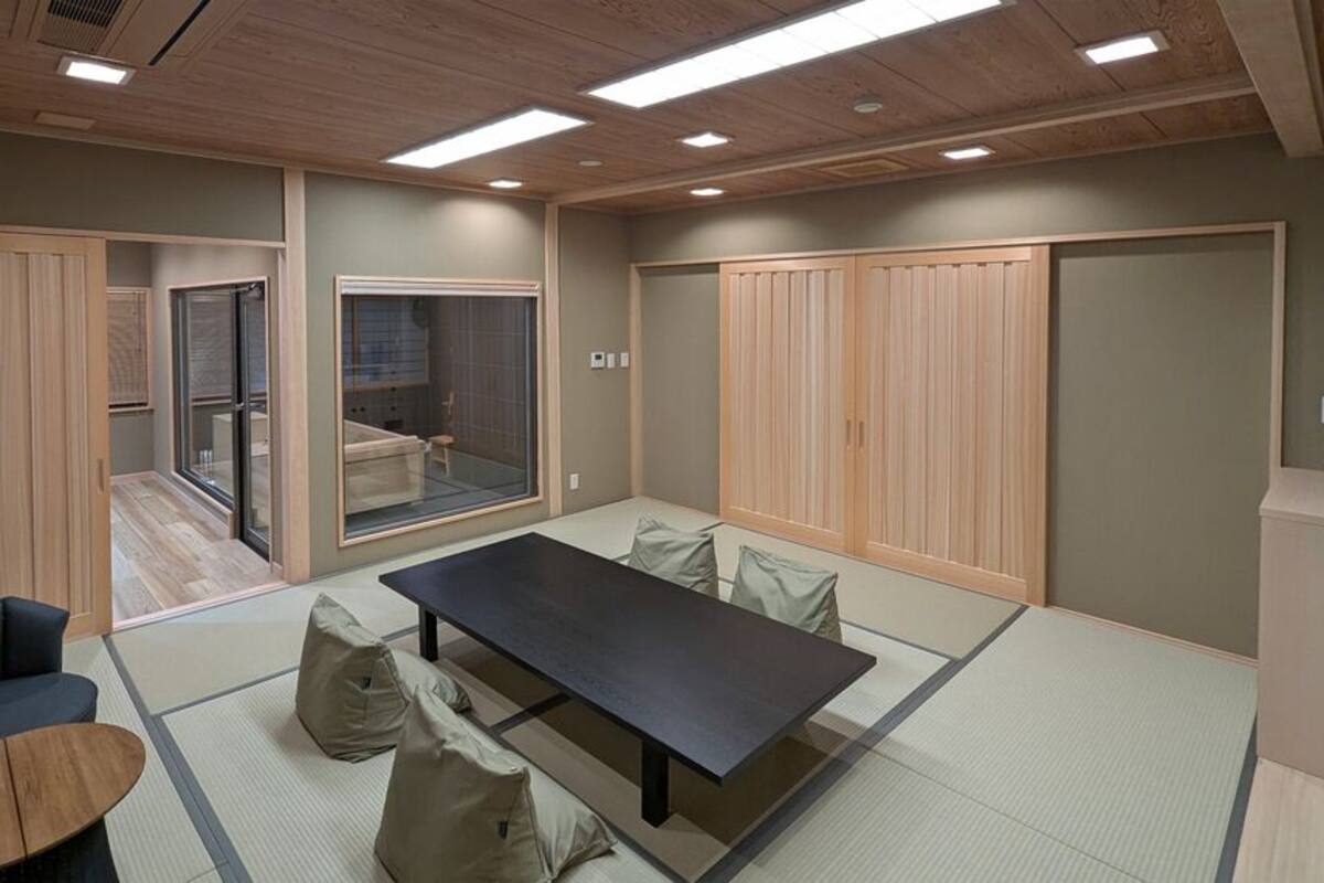 A room with tatami flooring, a low table, a sofa, and sliding doors.