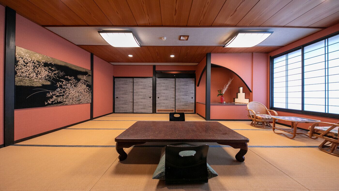 Ein Raum mit Tatami-Matten, einem niedrigen Tisch, Schiebetüren und traditionellen japanischen Möbeln.