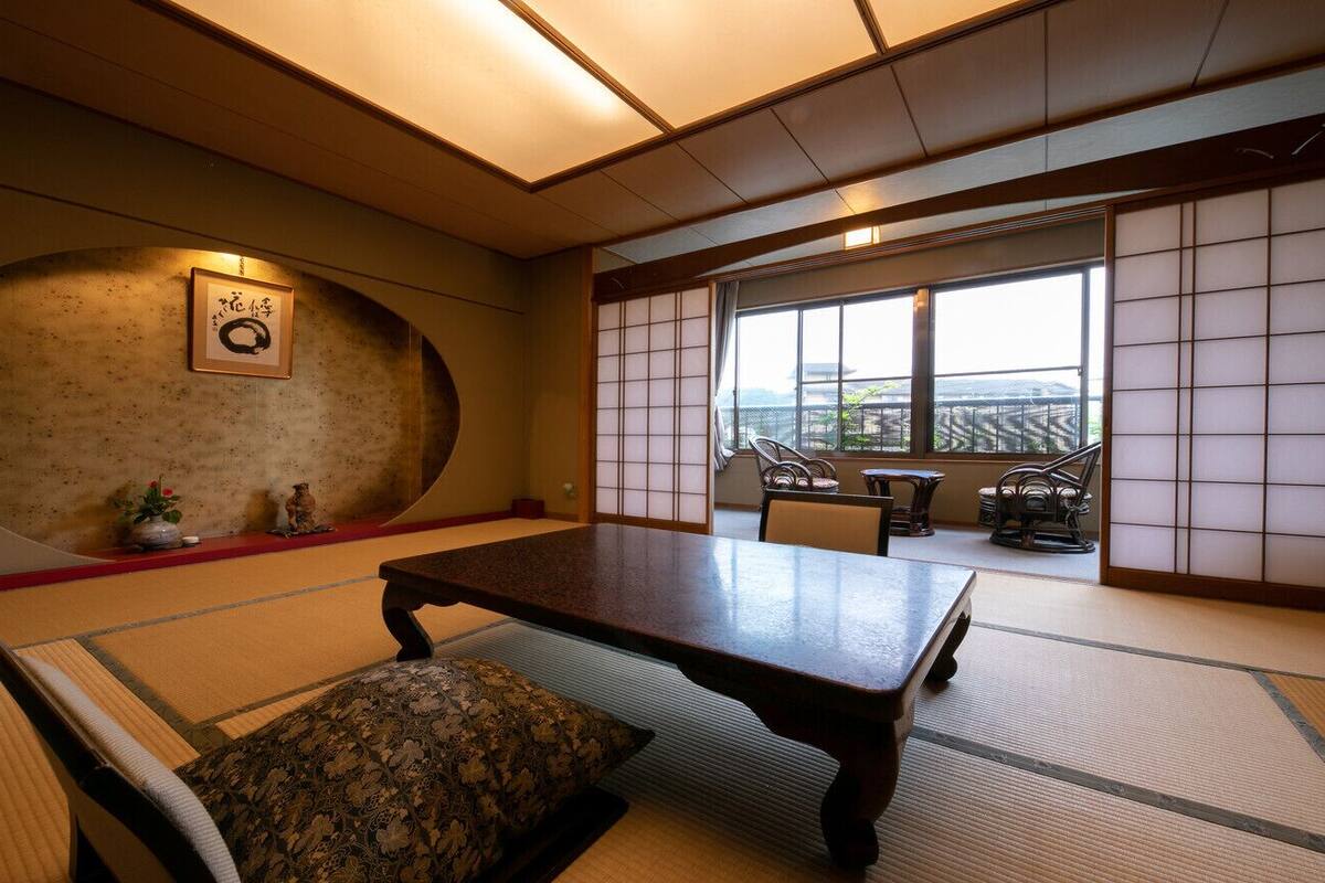 A traditional Japanese room with tatami flooring, a low table, and a view through shoji screens.
