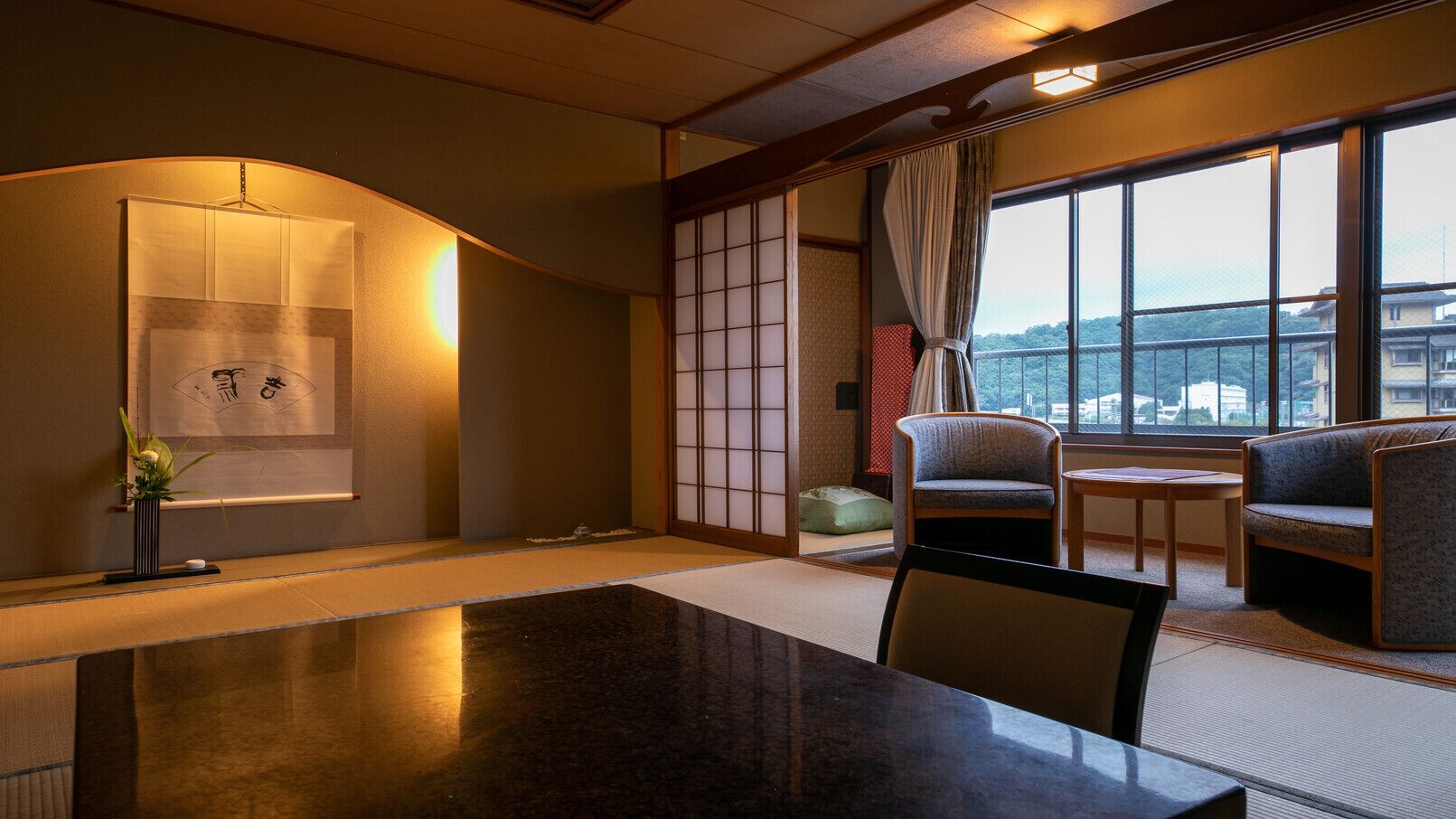 Ein traditioneller japanischer Raum mit Tatami-Böden, einem niedrigen Tisch, einer Couch und einer Schiebetür.