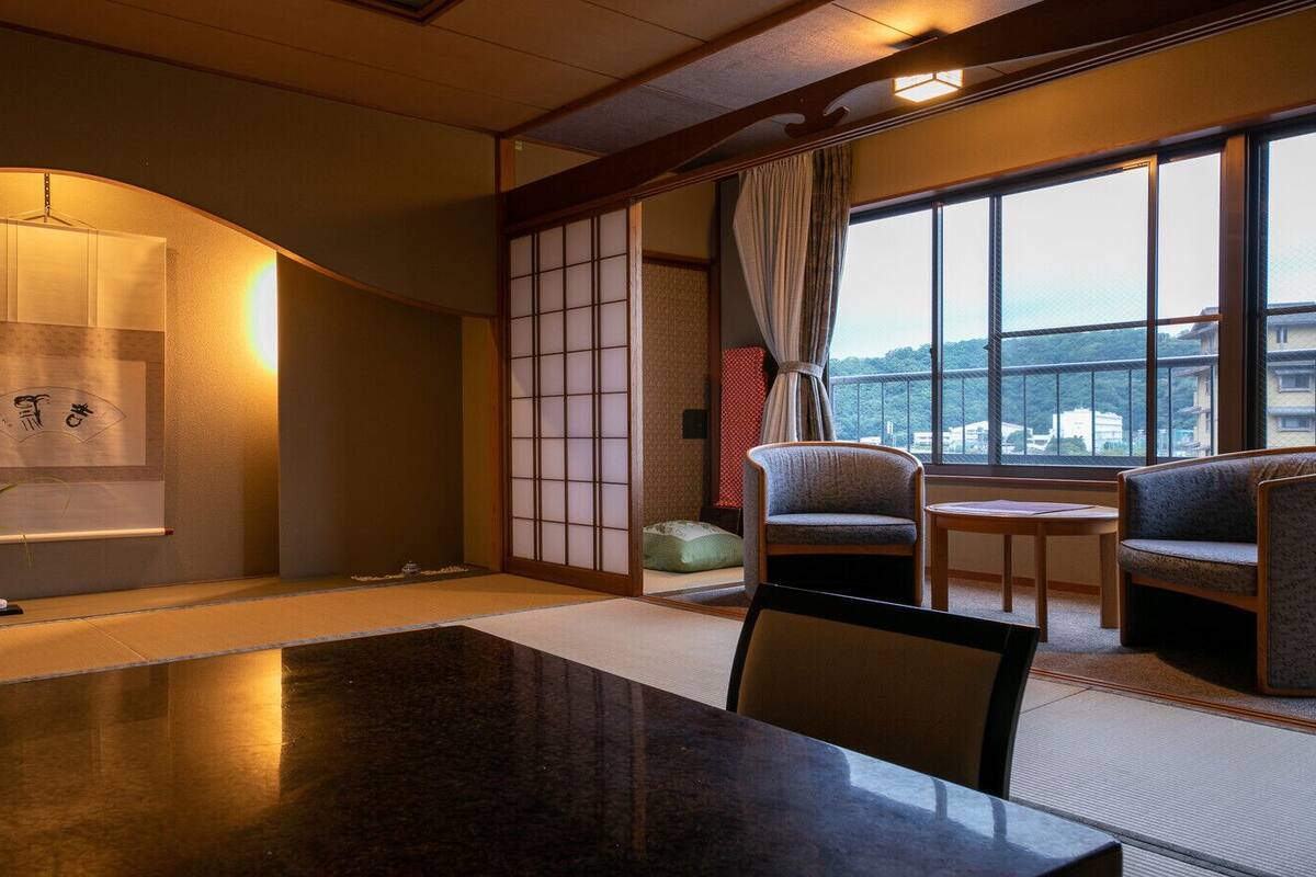 A traditional Japanese room with tatami flooring, a low table, a sofa, and a sliding door.