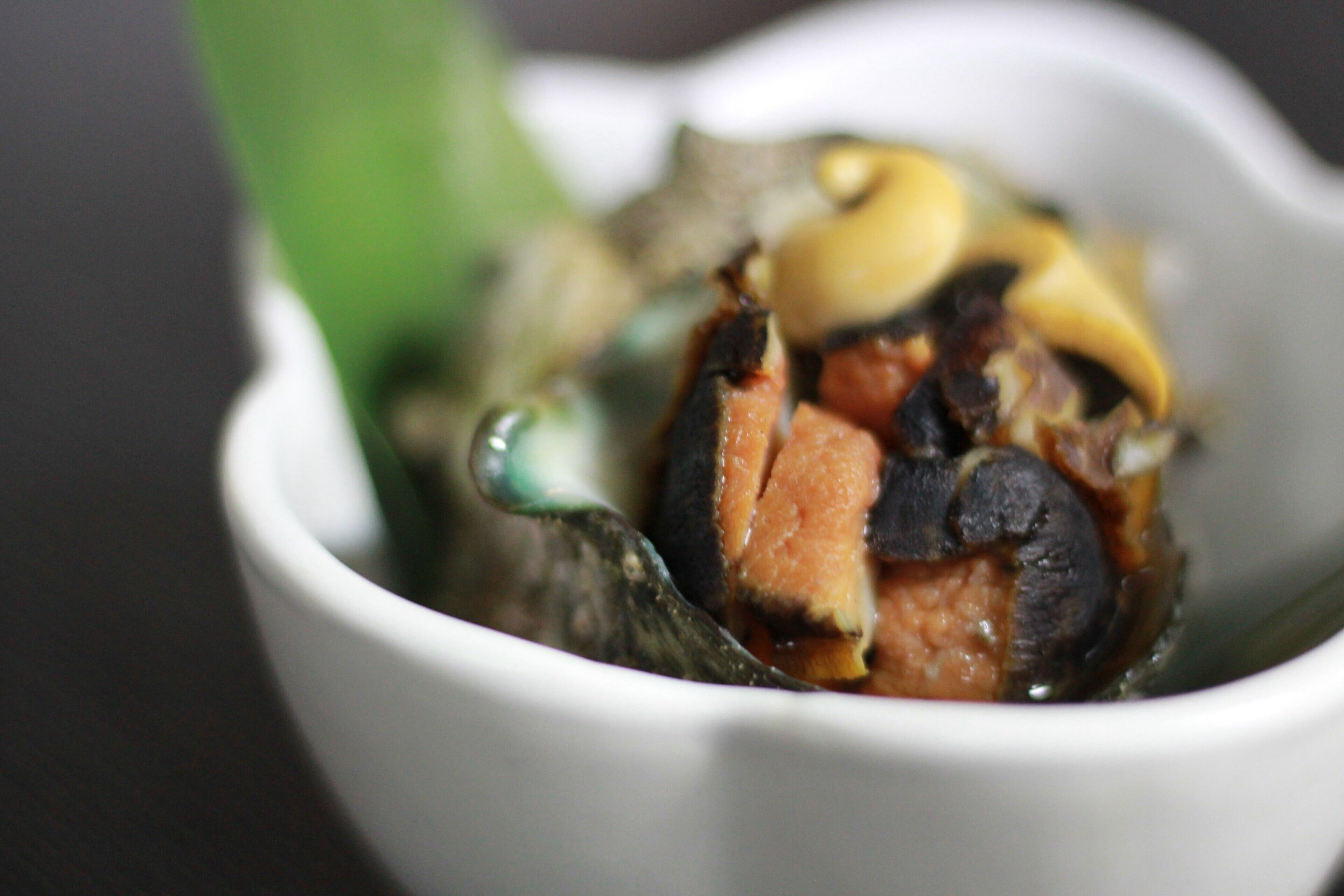A white bowl containing a seafood dish with various ingredients.