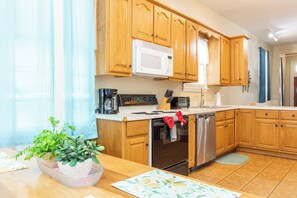 A kitchen with wooden cabinets, a white microwave, a stove, and a dishwasher.