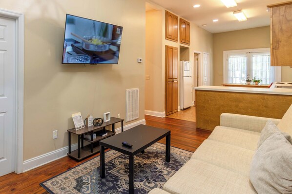 A living room with a sofa, a coffee table, and a TV mounted on the wall.