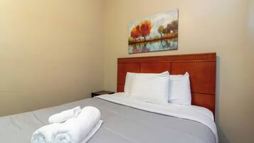 Quarto de hotel com cama, pintura de árvores de outono e cama bem arrumada com toalhas.