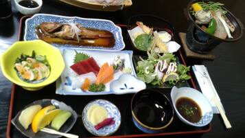 A tray with various Japanese dishes, including sashimi, sushi, and a salad.