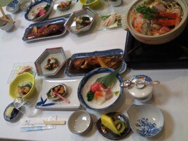 A variety of dishes on a table, including seafood and vegetables, with chopsticks and small bowls.