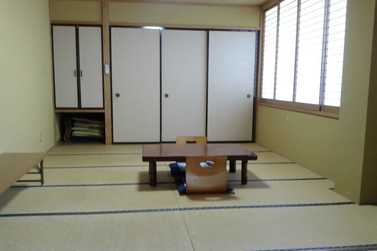 A tatami mat room with a low table, a chair, and sliding doors.