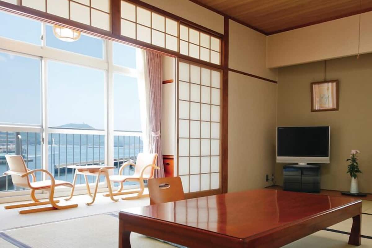 Une pièce de style japonais traditionnel, avec un sol recouvert de tatamis, une table basse et un téléviseur.