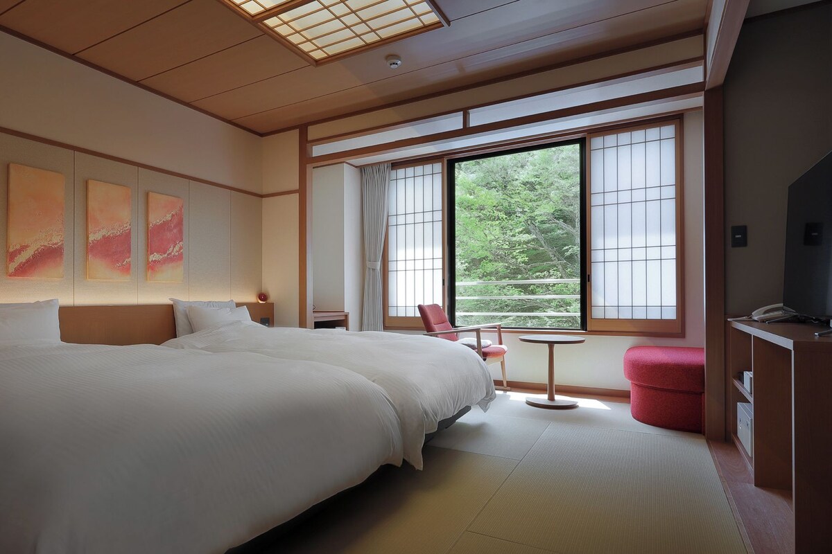 Una habitación de hotel con una cama grande, una mesita, una silla y un televisor.