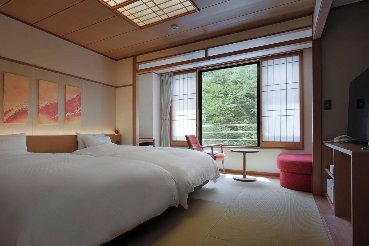 Une chambre d’hôtel avec un grand lit, une petite table, une chaise et un téléviseur.