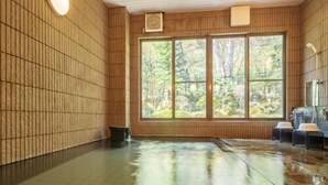 Un cuarto de aguas termales con paredes de madera, un ventanal grande y una zona de estar.