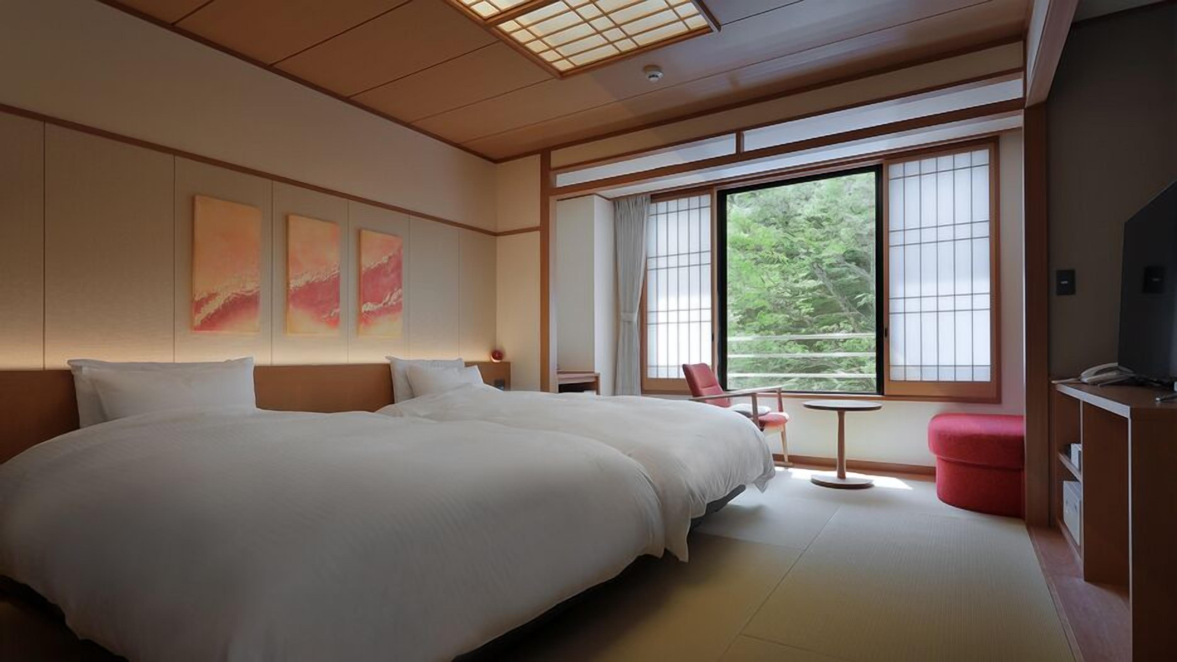 A hotel room with a large bed, a small table, a chair, and a TV.