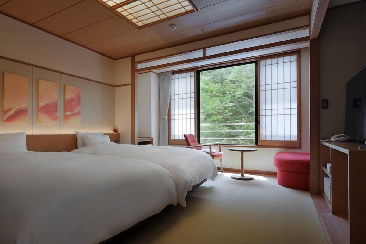 Une chambre d’hôtel avec un grand lit, une petite table, une chaise et un téléviseur.