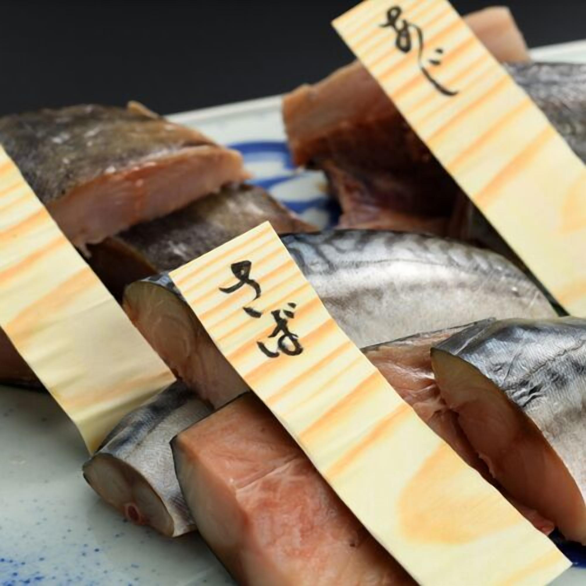 A plate with various fish cuts, each labeled with a wooden tag.