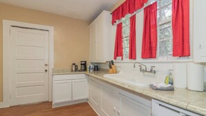 A kitchen with white cabinets, a sink, and a window with red curtains. - Downtown, Mins to Lakebottom Park-Our Midtown Nook (Columbus)