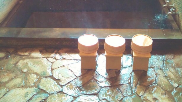 A stone-floored bathtub with a window above and three wooden stools in front. - Tenryuso (Otaki)